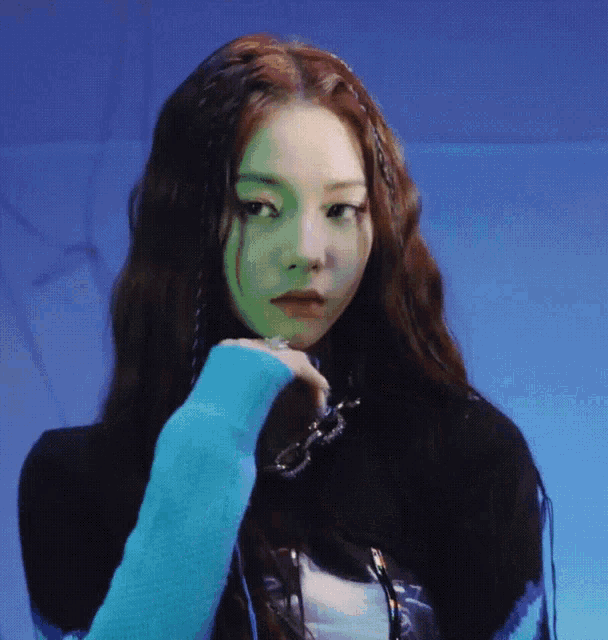 a woman with long hair is wearing a blue sweater and looking at the camera .