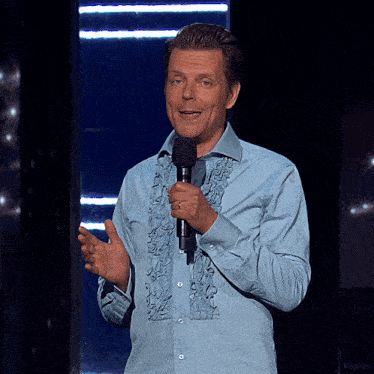 a man in a blue shirt is holding a microphone in his hand