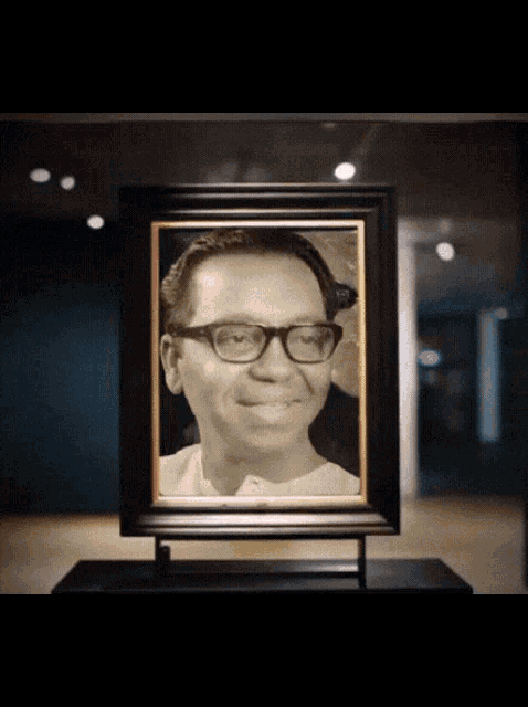 a framed portrait of a man with glasses is on display