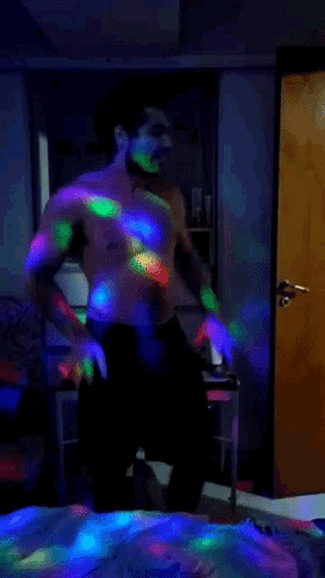 a shirtless man is dancing in a dark room with glowing lights
