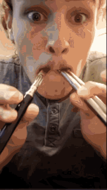 a man is holding a pair of chopsticks in his mouth and looking at the camera