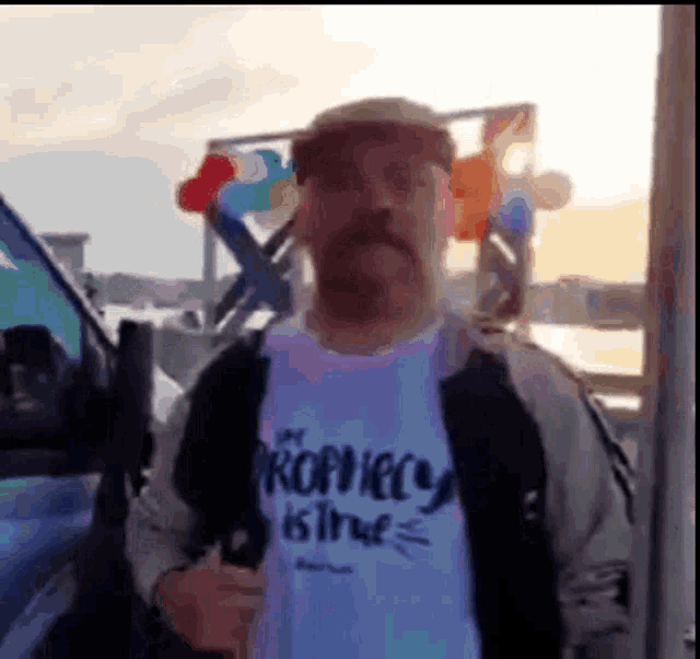 a man with a mustache is wearing a t-shirt that says the prophet is true