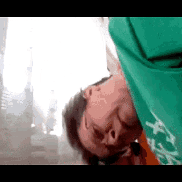 a man wearing a green shirt with the word x on it