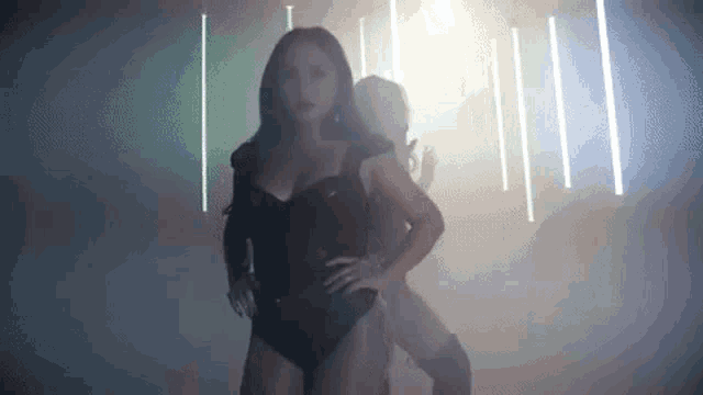 a woman in a black bodysuit is dancing in a dark room with smoke coming out of the ceiling .