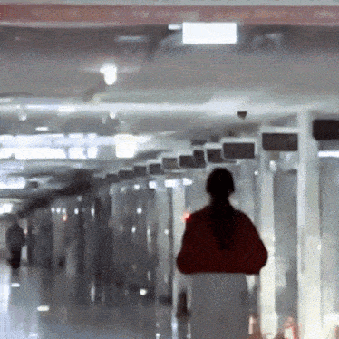 a woman in a red jacket walks through a hallway