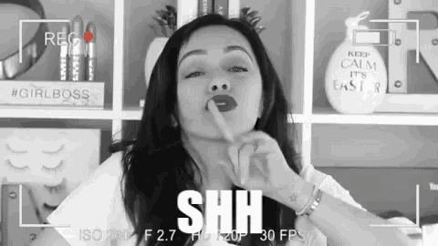 a black and white photo of a woman making a shhh sign