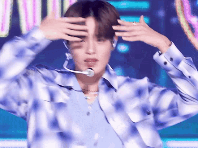 a man wearing a blue plaid shirt and a microphone covering his face