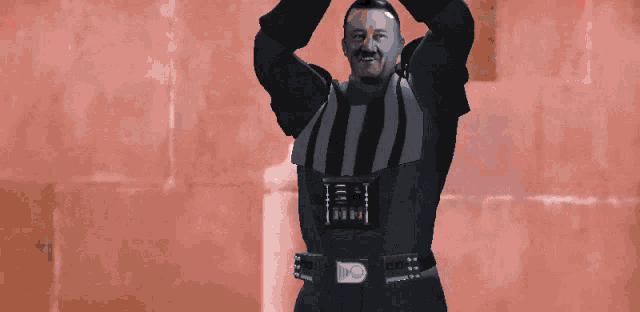 a man in a black and white striped shirt is holding a red light saber