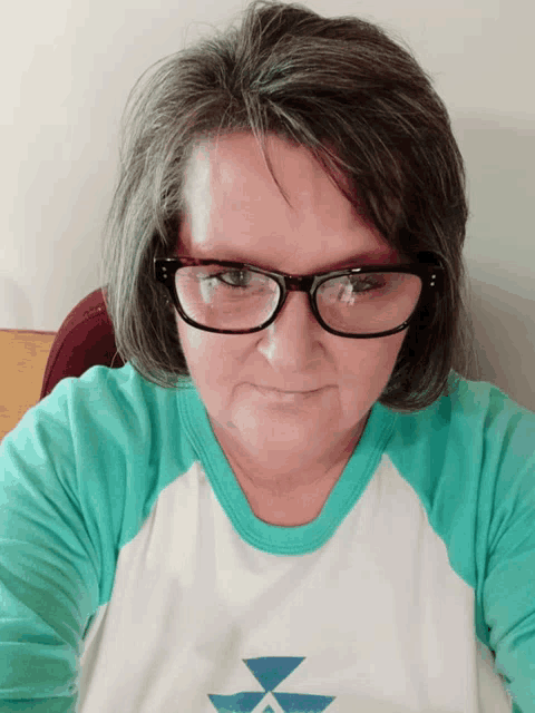 a woman wearing glasses and a blue and white shirt with a blue triangle on it