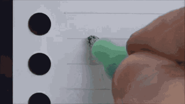 a person is writing on a piece of paper with a green pen .
