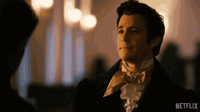 a man in a tuxedo is standing in a dark room with a netflix logo on the bottom