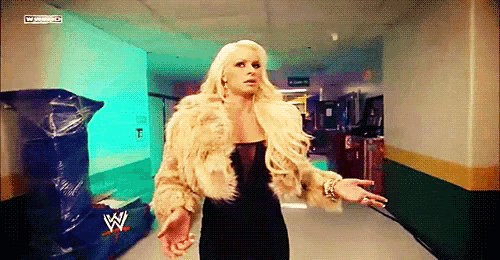 a woman in a fur coat is walking down a hallway with a wwe logo on the wall