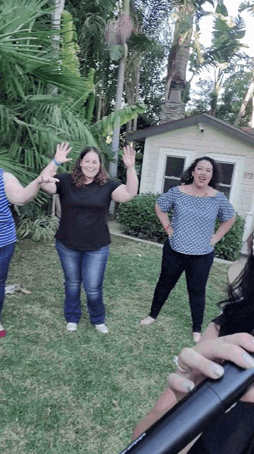 a group of women are standing in a circle in front of a house that has the number 23 on the front