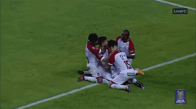 a group of soccer players are celebrating a goal with a live fc logo in the background