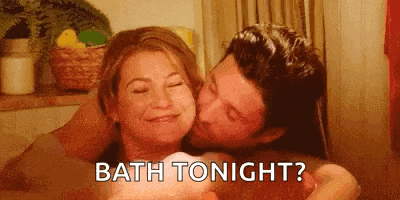 a man is kissing a woman on the cheek in a bath tub .