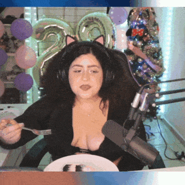 a woman wearing headphones and a cat ear headband is eating cake
