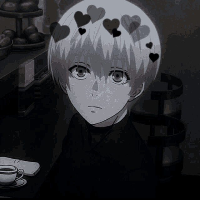 a boy with hearts in his hair is sitting at a table next to a cup of coffee
