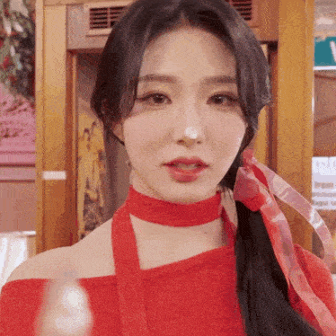 a close up of a woman wearing a red top and a red scarf around her neck