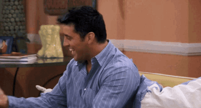 a man in a blue and white striped shirt is smiling