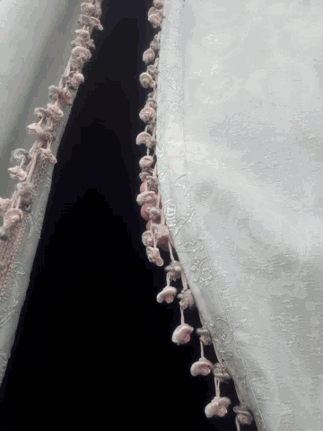 a close up of a white cloth with a pink fringe