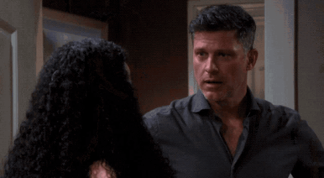 a man in a black shirt is standing next to a woman with curly hair