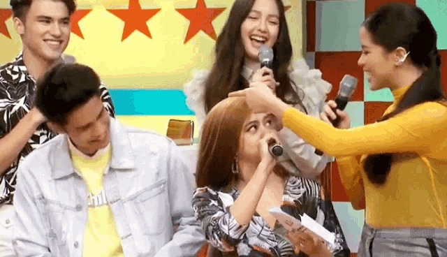 a woman in a yellow shirt is putting a microphone on another woman 's head .