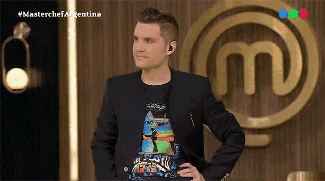 a man stands in front of a masterchef argentina sign