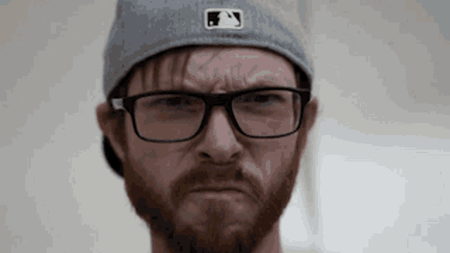 a man with a beard wearing glasses and a hat with a ny logo on it