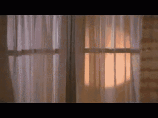 a window with white curtains and a light shining through them