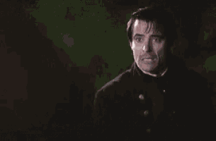 a man in a black jacket and red shirt is making a funny face