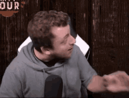 a man in a hoodie is talking into a microphone .