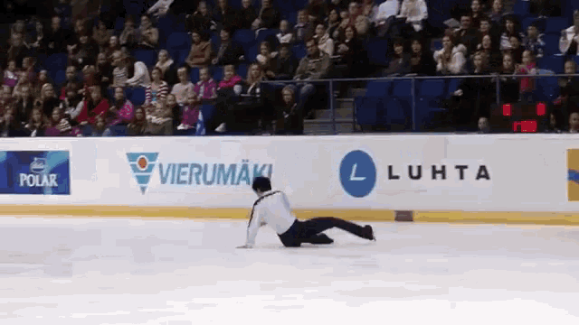 a skater falls on the ice in front of a banner that says polar