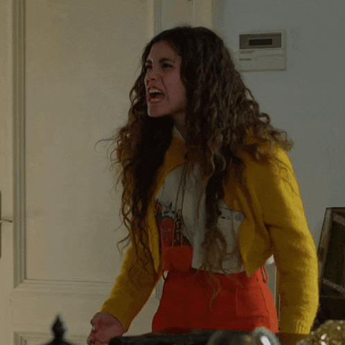 a woman wearing a yellow jacket and red skirt is screaming