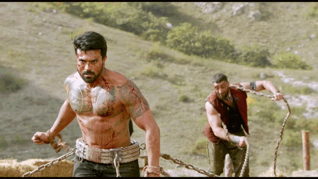 a man with a tattoo on his chest is chained to another man with chains