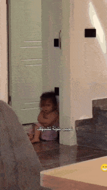 a baby is sitting on the floor in a room with arabic writing