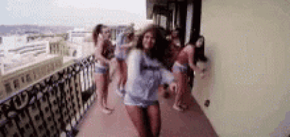 a woman is dancing on a balcony with a group of people .