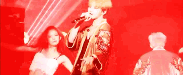 a man is singing into a microphone while a woman watches .