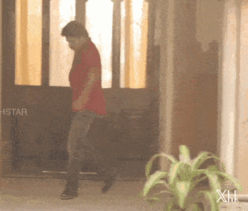 a man in a red shirt is walking in front of a door that says hstar on it