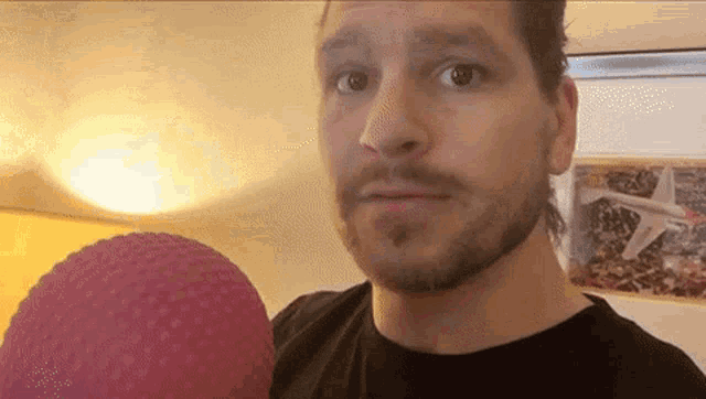a man with a beard is holding a pink ball in front of him .