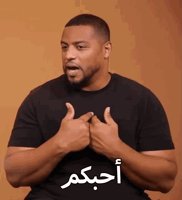 a man wearing a black shirt with arabic writing on it giving a thumbs up