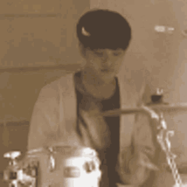 a man in a white coat is playing drums in a sepia tone photo .
