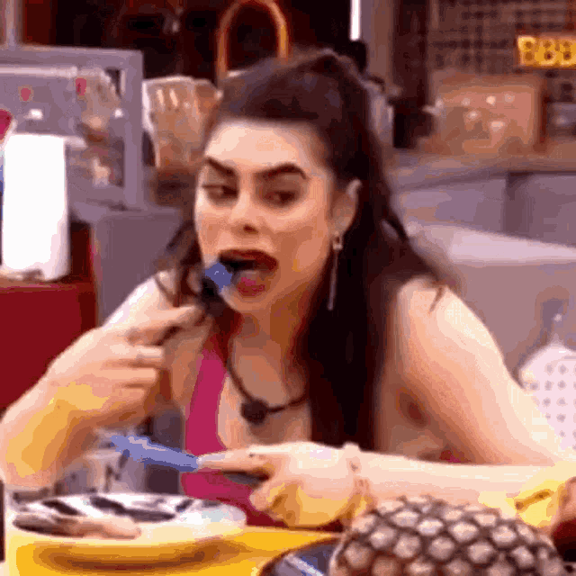 a woman is sitting at a table eating a piece of food with a fork .