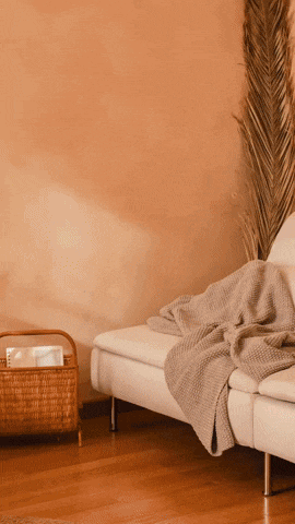 a couch with a blanket on it and a basket with magazines in it