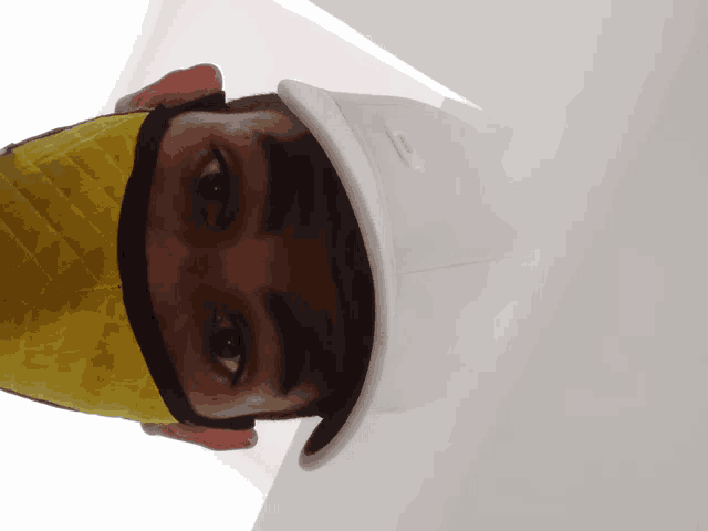 a man wearing a yellow face mask and a white hat