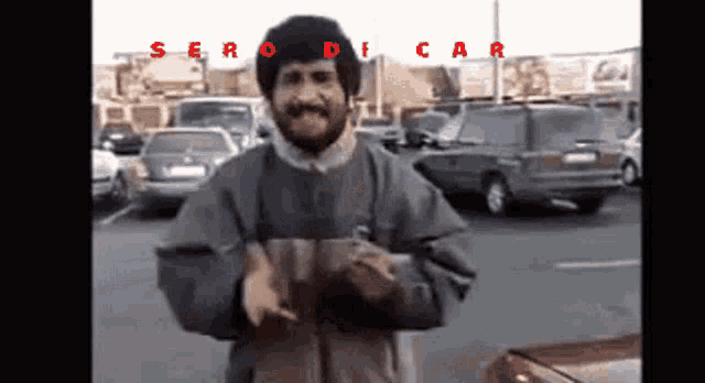 a man with a mustache is standing in a parking lot with cars in the background and the words serodica on the bottom right