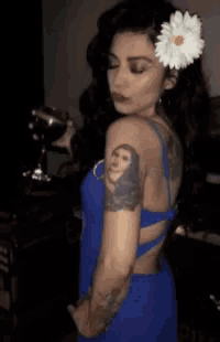 a woman with a flower in her hair has a tattoo on her arm