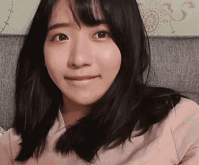 a woman with long black hair is sitting on a couch and making a funny face