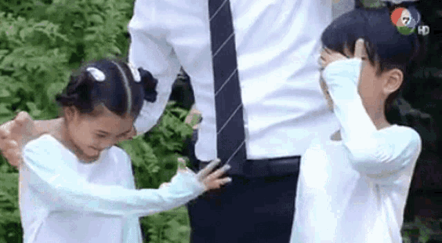 a man in a suit and tie is standing next to two little girls in white shirts .