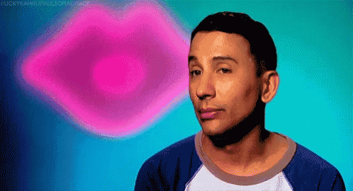 a man in a blue shirt is standing in front of a pink heart shaped lips .