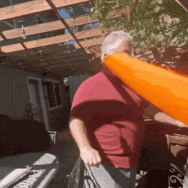a man in a red shirt is holding an orange cone over his head